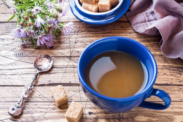 Tazza di caffè nero fumante caldo con i cubi dello zucchero sulla tavola di legno