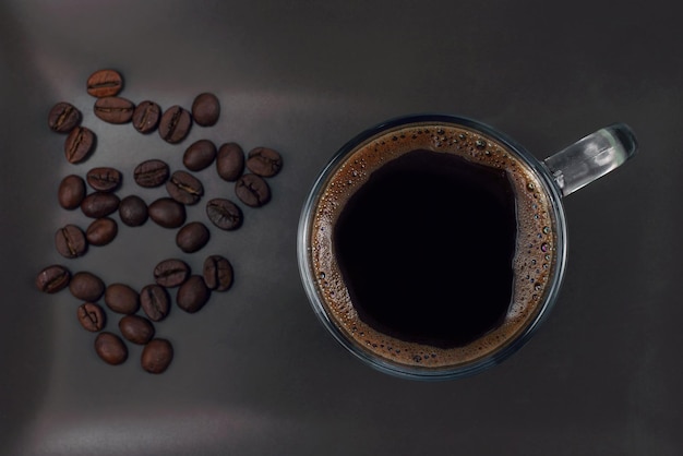 Tazza di caffè nero su un piatto marrone con chicchi di caffè