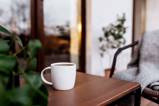 Tazza di caffè o tè sul tavolo sulla terrazza in legno marrone durante il tramonto. Rilassamento, concetto di vita di campagna silenziosa