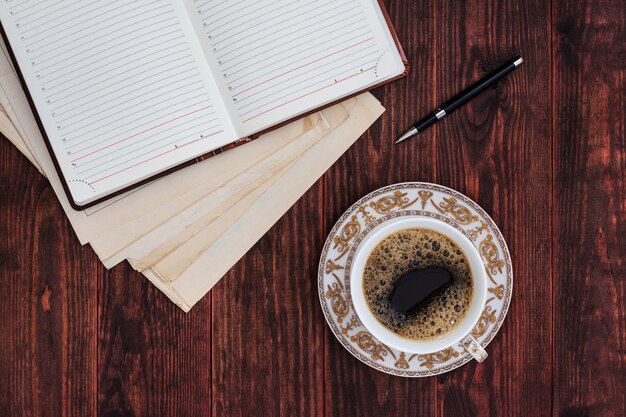 Tazza di caffè, penna e quaderno aperto