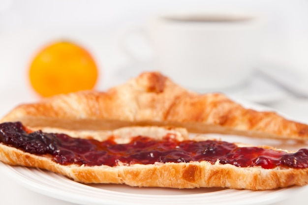 Tazza di caffè posta dietro un croissant