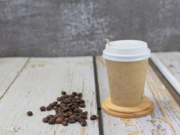 Tazza di caffè riciclata sulla tavola di legno con i chicchi di caffè