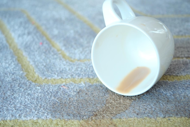 Tazza di caffè rovesciata sul tappeto di colore grigio