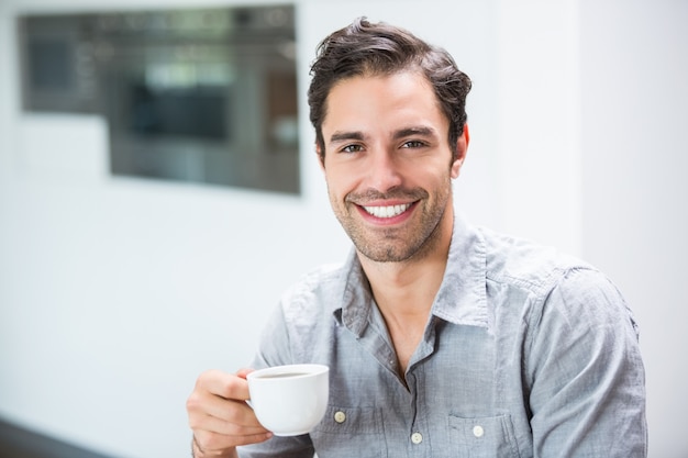 Tazza di caffè sorridente della tenuta del giovane