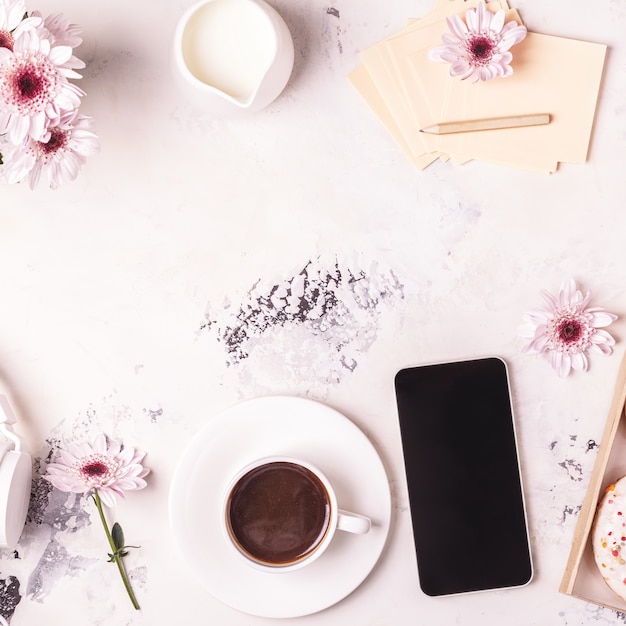 Tazza di caffè su un piattino e uno smartphone