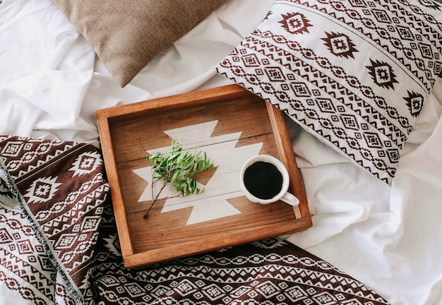 Tazza di caffè su un vassoio con un ramo verde in camera da letto