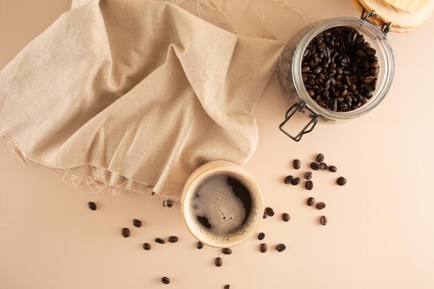 Tazza di caffè su uno sfondo beige con chicchi di caffè e tovaglia in vista aerea