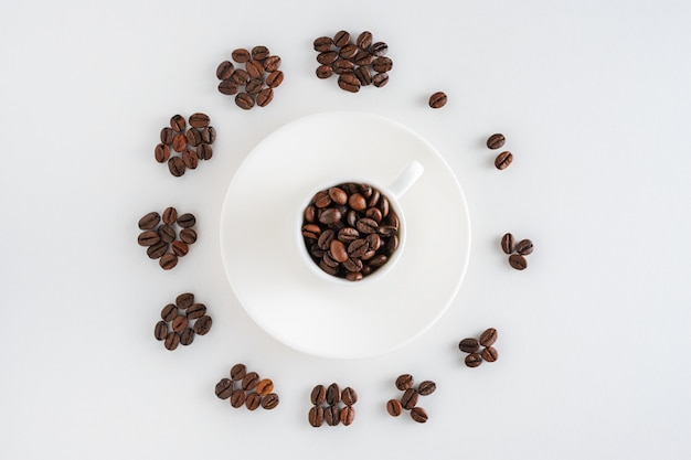 Tazza di caffè sul piattino e chicchi di caffè in forma di un orologio