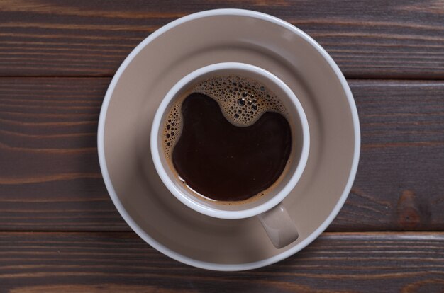 Tazza di caffè sul primo piano fondo di legno, vista dall'alto