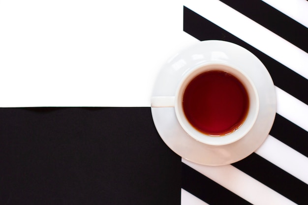 Tazza di caffè sul tavolo bianco e nero con strisce in stile minimal