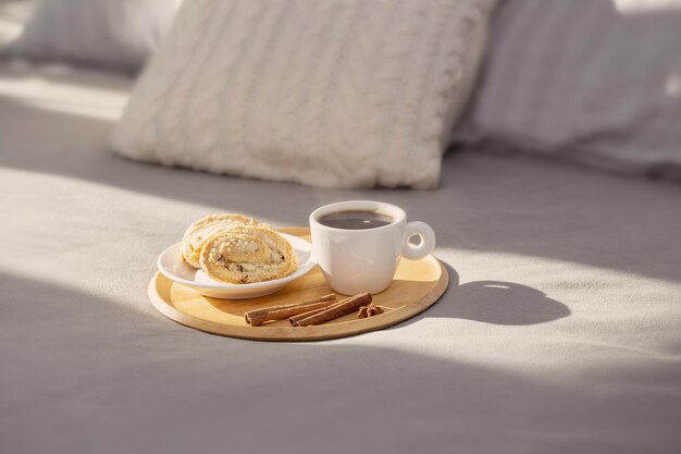 Tazza di caffè sul vassoio di legno sul letto in un'accogliente camera da letto