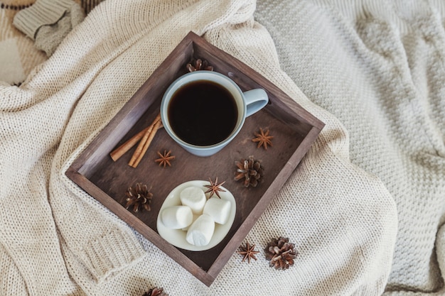 Tazza di caffè sul vassoio in legno rustico con marshmallow dolce e caldo maglione di lana