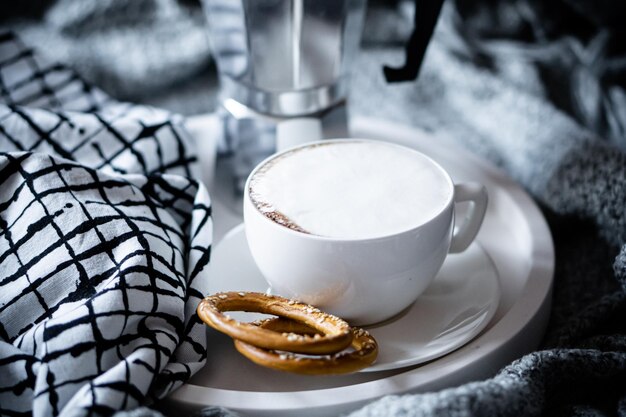 Tazza di caffè sul vassoio nell'accogliente inverno cattivo con coperta di lana