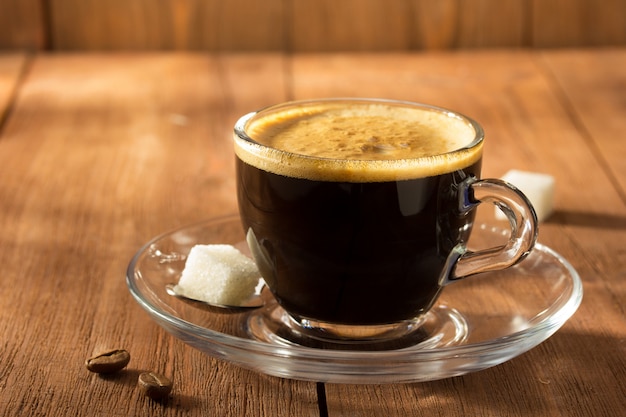 Tazza di caffè sulla lastra di vetro sulla tavola di legno