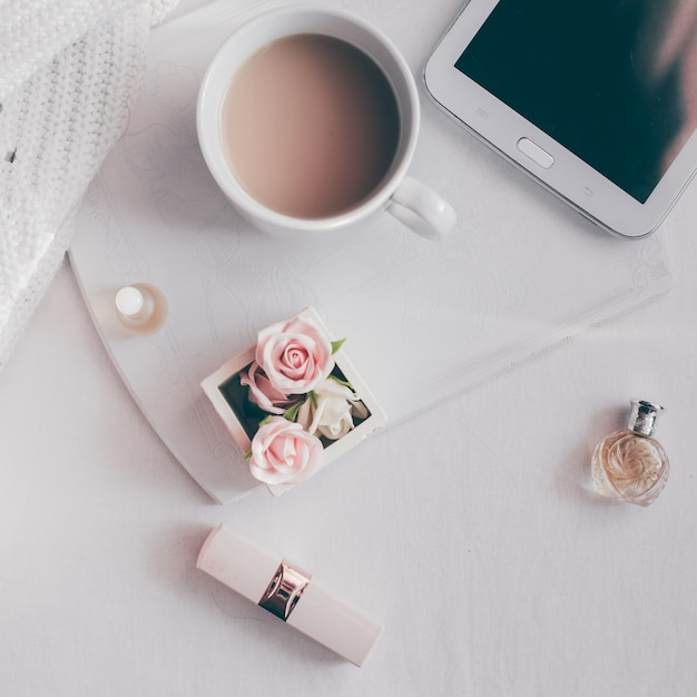 Tazza di caffè, tablet e fiori su un tavolo