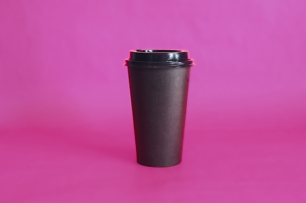 Tazza di caffè usa e getta nera sul rosa.