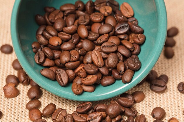 Tazza di caffè verde con grani e sfondo di stoffa di rafia