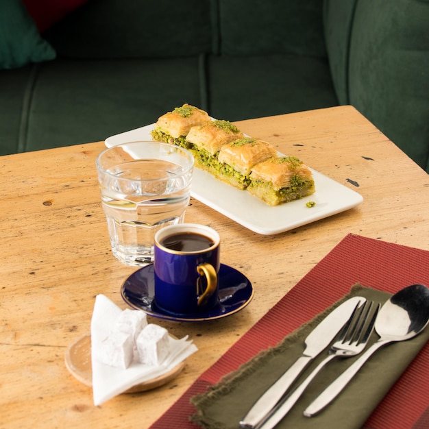 Tazza di caffè vicino a un bicchiere d'acqua e baklava