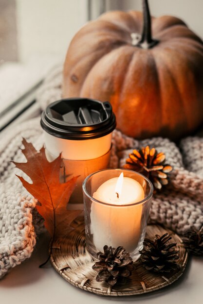 Tazza di caffè, zucca, foglie di autunno secche sulla finestra.