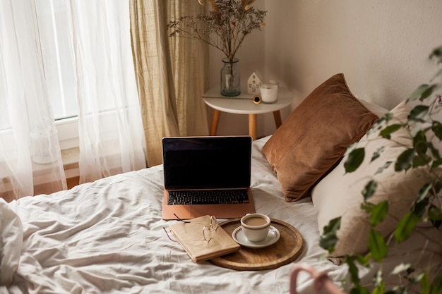 Tazza di cappuccino caldo un libro occhiali un laptop sul letto Lavora online a casa Home Office Internet