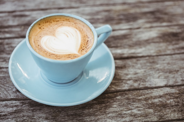 Tazza di cappuccino con arte del caffè sulla tavola di legno alla caffetteria