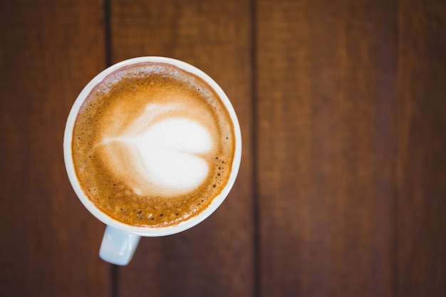 Tazza di cappuccino con arte del caffè sulla tavola di legno