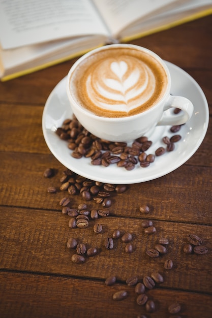 Tazza di cappuccino con caffè art e chicchi di caffè