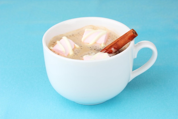 Tazza di cappuccino con marshmallow e cannella su sfondo blu