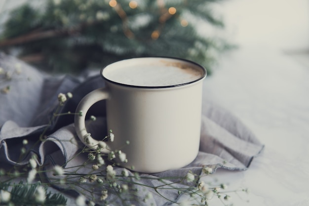 Tazza di cappuccino con rami di abete e fiori di gipsofila