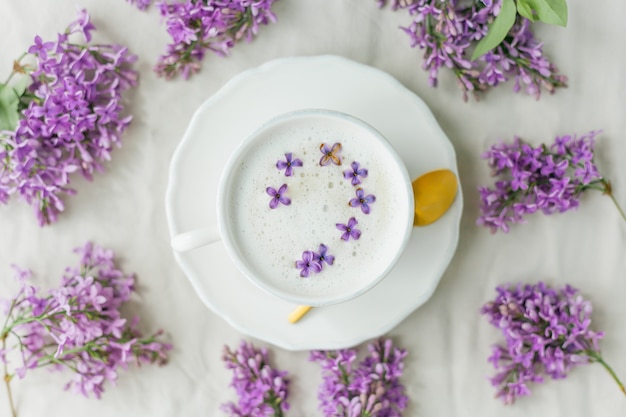 Tazza di cappuccino su una superficie beige. Fiori lilla.