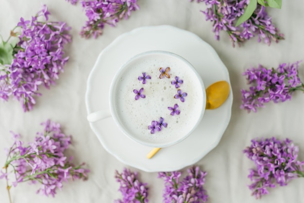 Tazza di cappuccino su una superficie beige. Fiori lilla.