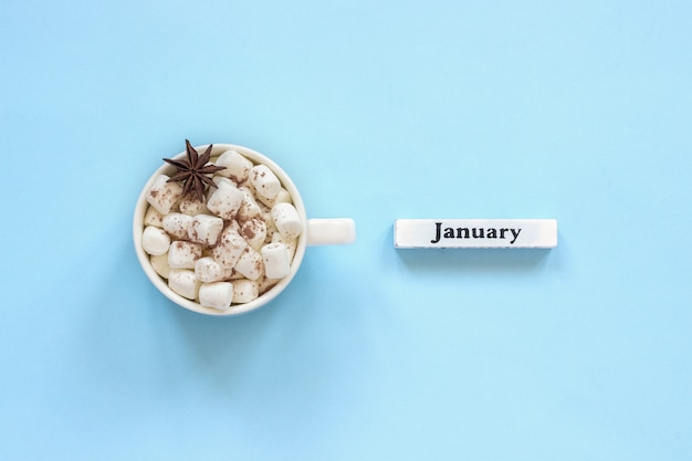 Tazza di caramelle gommosa e molle del cacao e calendario gennaio su fondo blu