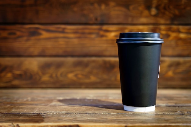 Tazza di carta da caffè su sfondo di tavolo in legno Bere caffè da asporto mockup