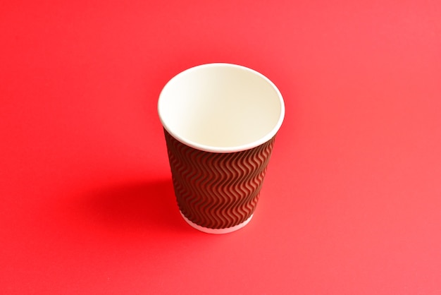 Tazza di carta marrone su sfondo rosso. Copia spazio.