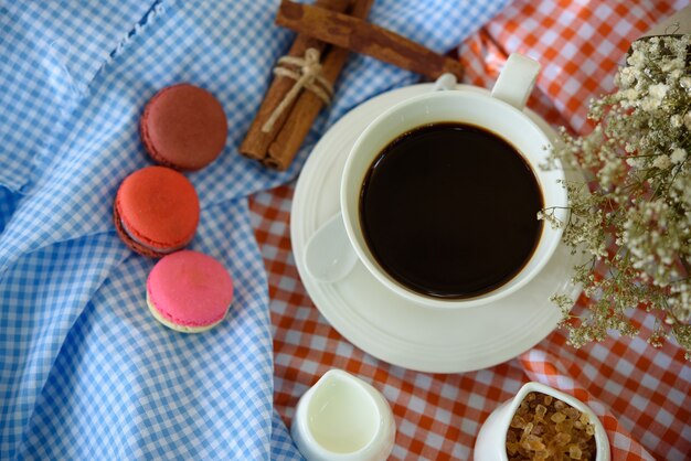 Tazza di ceramica di vista superiore di caffè nero e maccherone con latte sulla tavola di legno.