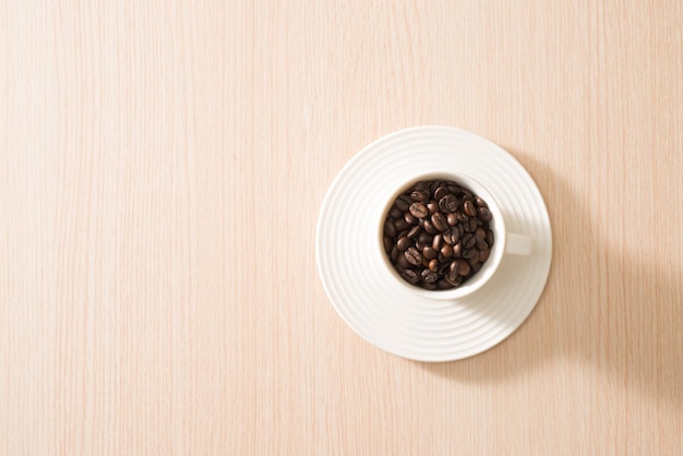 Tazza di chicchi di caffè pieni sullo sfondo di legno