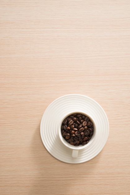 Tazza di chicchi di caffè pieni sullo sfondo di legno