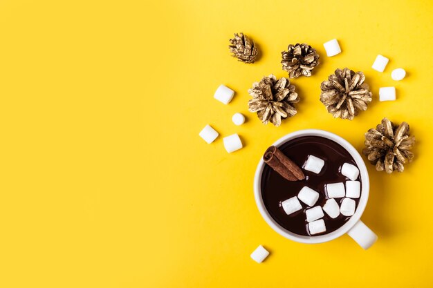 Tazza di cioccolata calda con cannella e marshmallow su sfondo giallo. Bevanda invernale di Natale riscaldante.