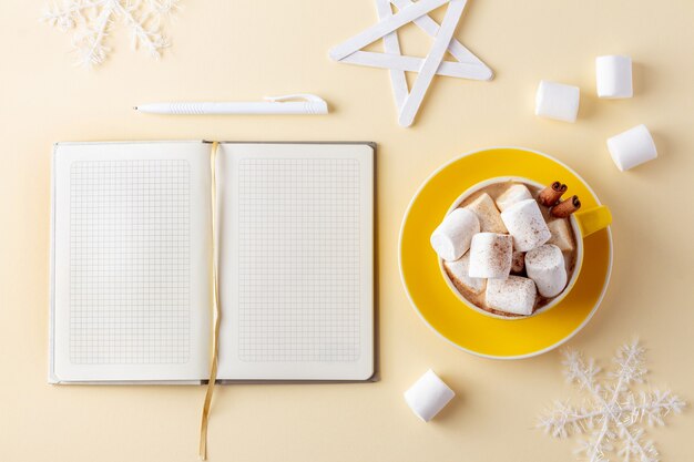 Tazza di cioccolata calda con marshmallow accanto al blocco note di carta