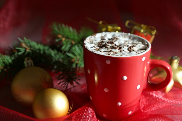 Tazza di cioccolata calda con panna a colori, sul tavolo, su sfondo di decorazioni natalizie