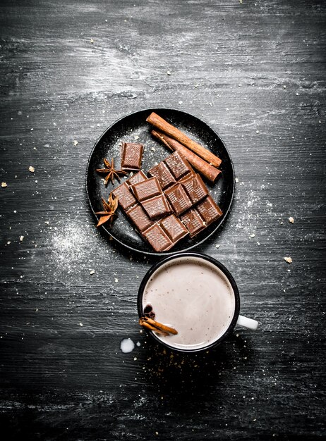 Tazza di cioccolata calda con stecca di cannella e fette di cioccolato fondente ..