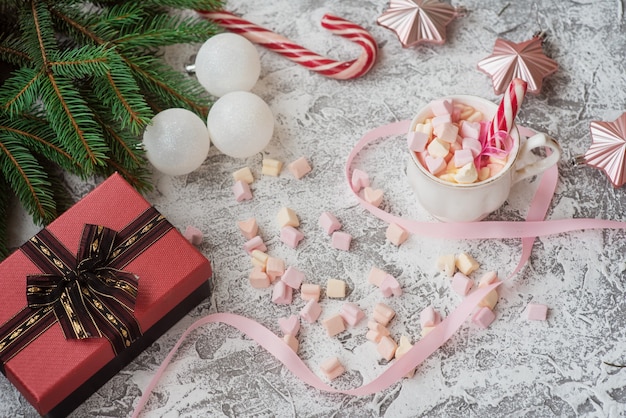 Tazza di composizione di Capodanno o Natale con marshmelow tra Capodanno, giocattoli, stelle, rami di abete e regali