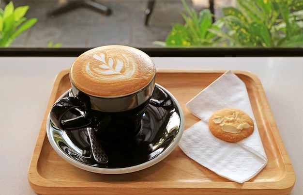 Tazza di delizioso cappuccino con un biscotto al burro sul tavolino della finestra