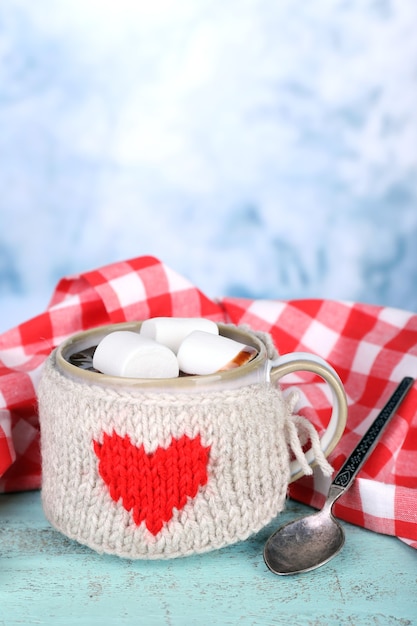 Tazza di gustosa cioccolata calda, su un tavolo di legno, su sfondo chiaro