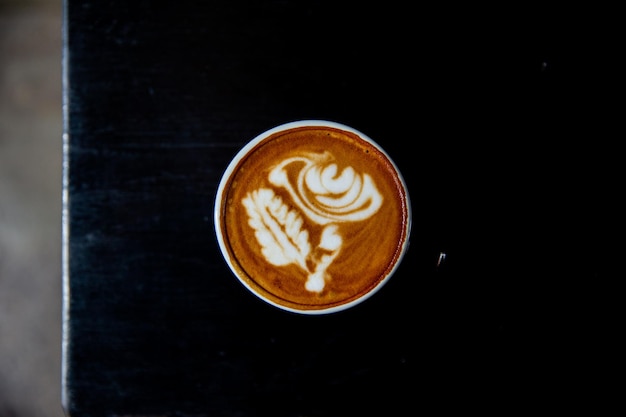 Tazza di gustoso cappuccino con latte art su sfondo nero tavolo