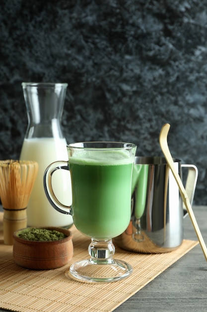 Tazza di latte matcha e accessori da realizzare su un tavolo grigio strutturato