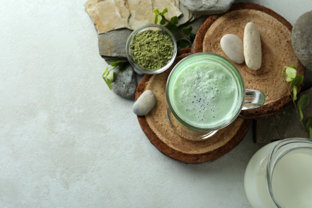 Tazza di latte matcha e accessori da realizzare su un tavolo strutturato bianco