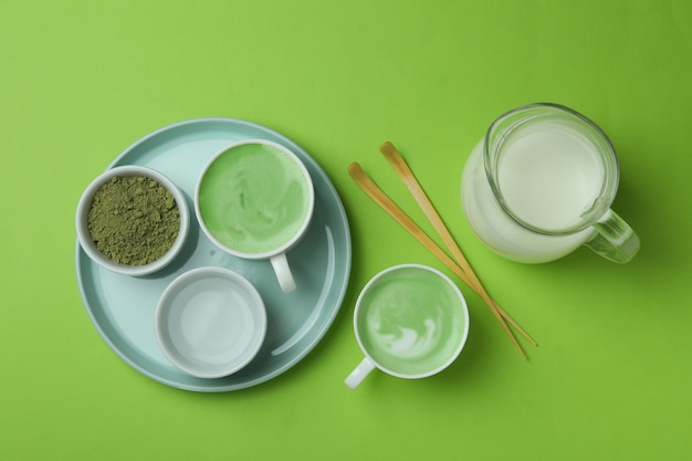 Tazza di latte matcha e accessori per fare su sfondo verde