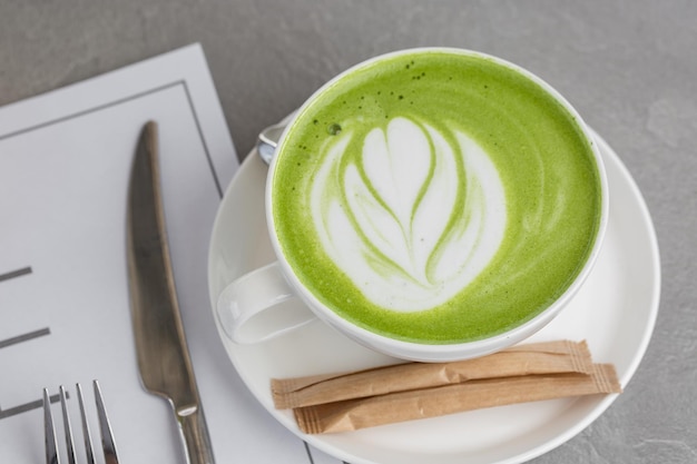 Tazza di matcha latte. Foto di alta qualità. Matcha, tè verde latte in una tazza. Sfondo di pietra grigia. Avvicinamento. Vista dall'alto.