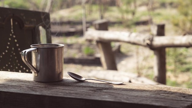 Tazza di metallo e un cucchiaio su un tavolo di legno in giardino